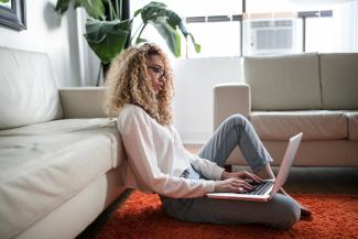 woman sitting on floor and leaning on couch using laptop by Thought Catalog courtesy of Unsplash.
